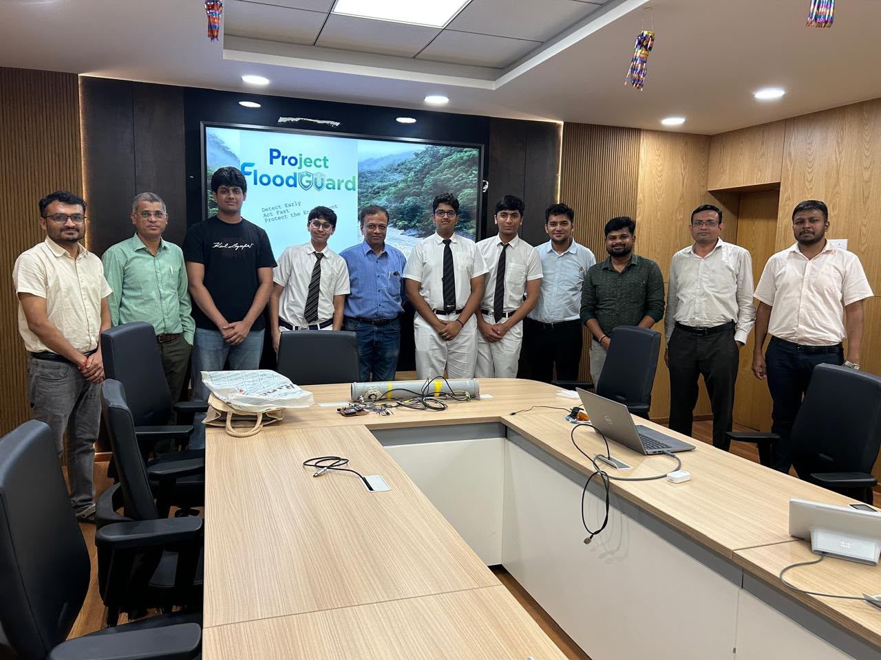 The FloodGuard team standing with municipal officials in a meeting room, with a Project FloodGuard slide on the screen