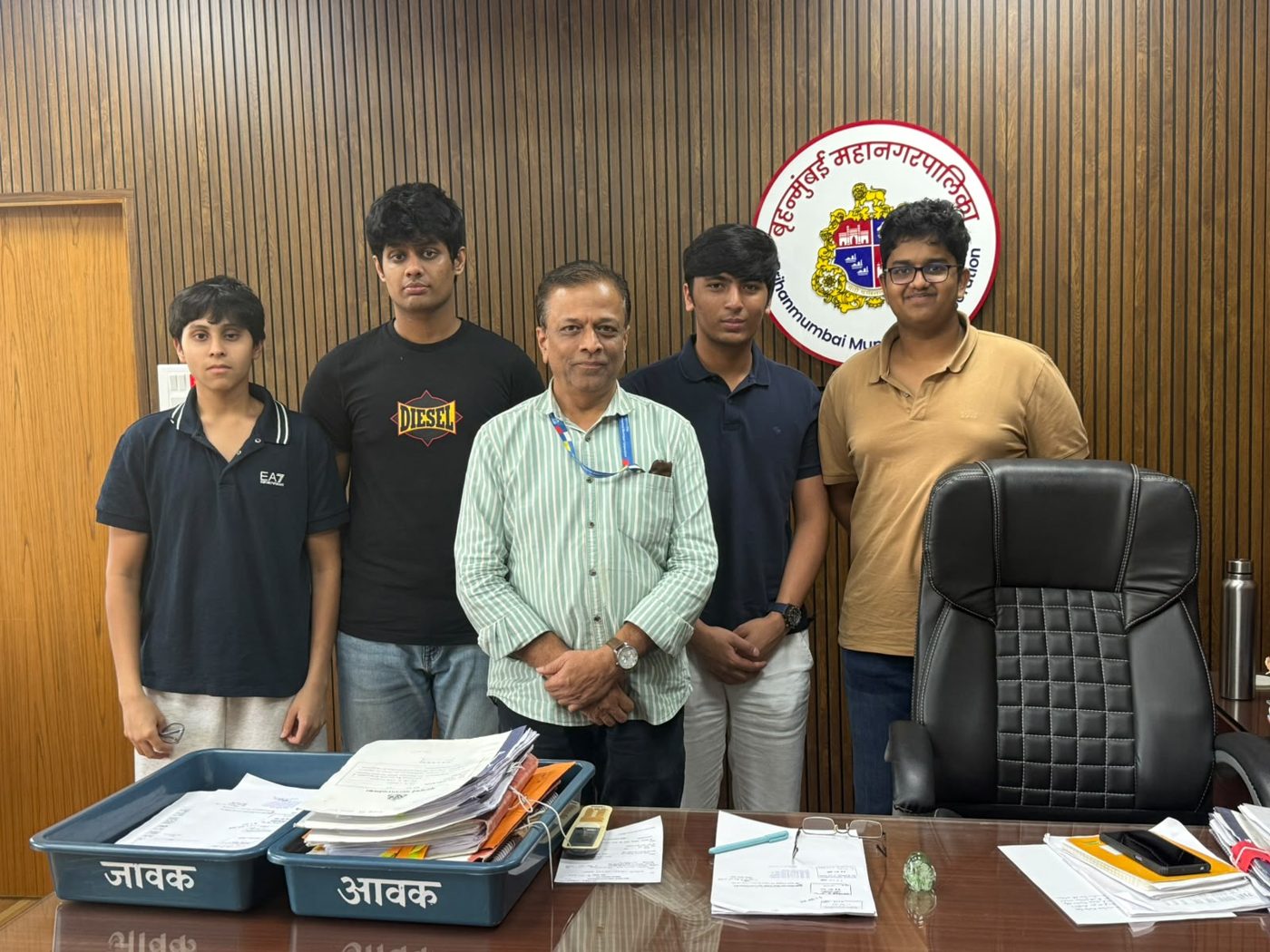 Four team members with a senior municipal official at his desk in a BMC office